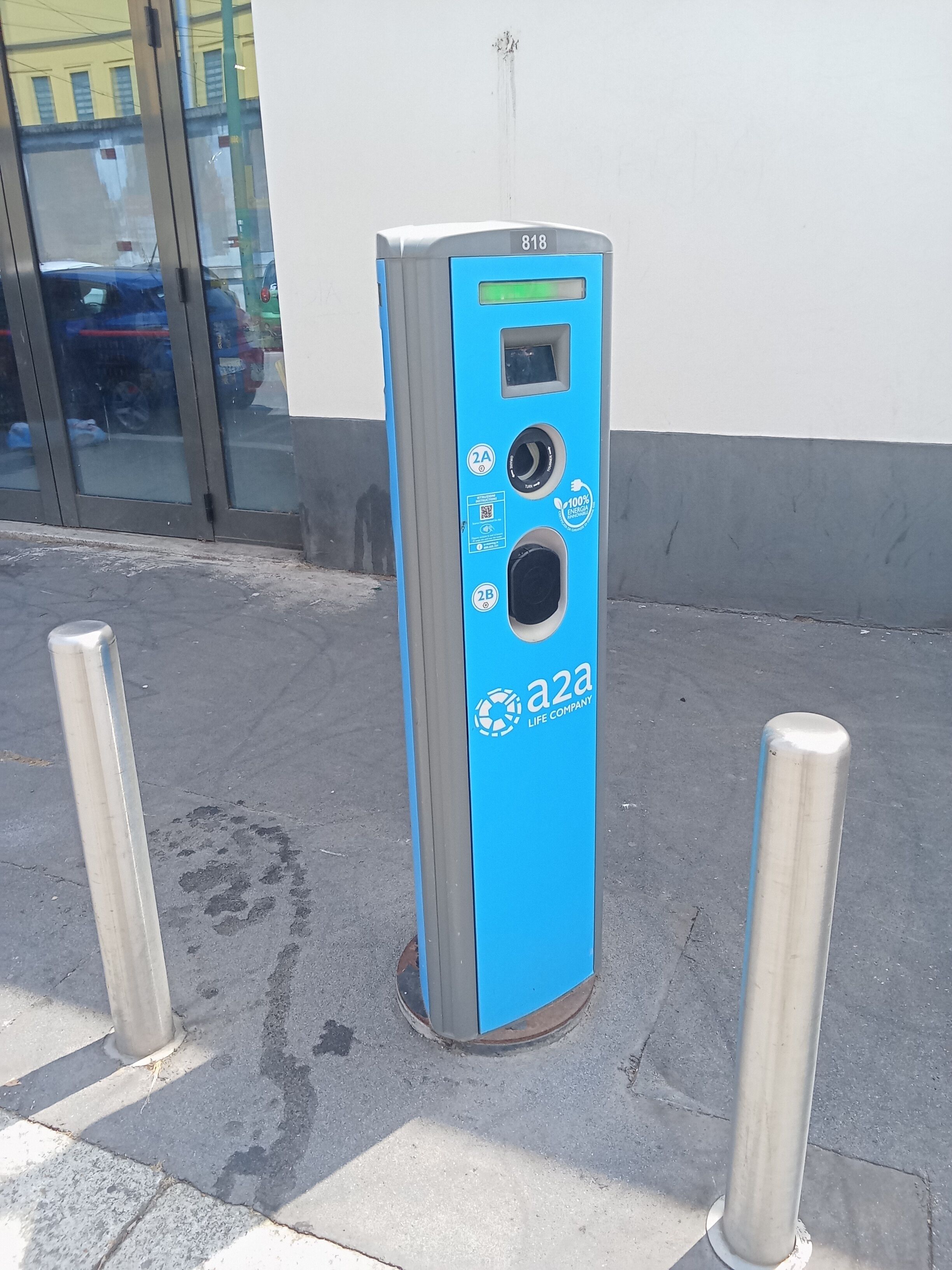 Une borne de recharge pour véhicules électriques, de couleur bleue, dotée d’un code QR et du logo de la société a2a Life Company.