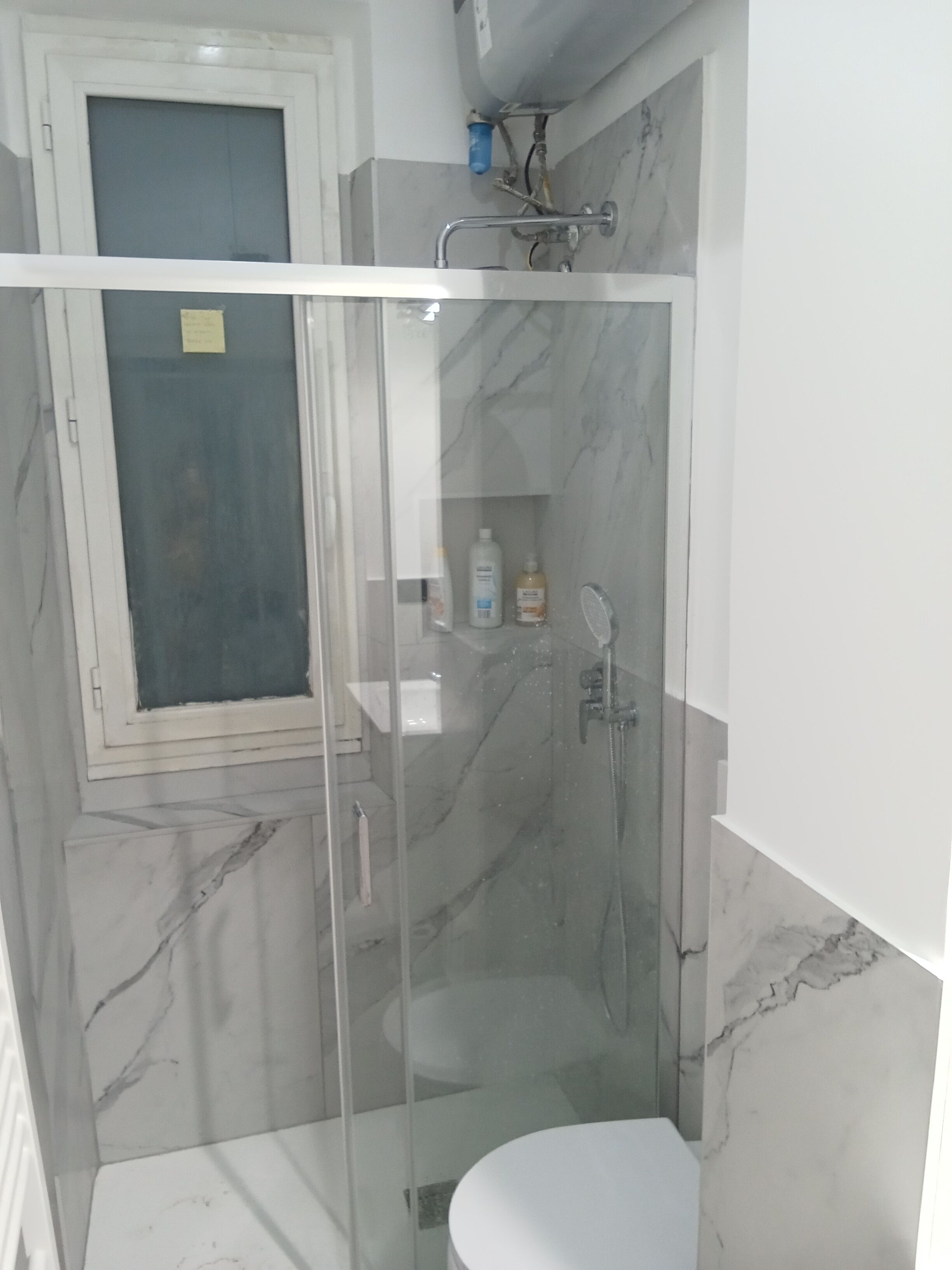 A bathroom with a glass-enclosed shower, a toilet, and a sink.