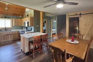 Une cuisine dotée de meubles en bois, d’un îlot central et d’un coin repas avec une table et des chaises.