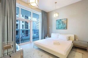 Une chambre d’hôtel moderne avec un grand lit, une cloison en verre, un bureau et un tableau au mur.