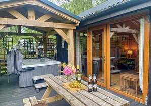 A wooden deck with a hot tub, picnic table, and wine bottles. - Seil Log Cabin - sleeps 5 guests  in 2 bedrooms (Taynuilt)