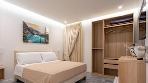 A modern bedroom with a bed, a wardrobe, a desk, and a painting on the wall. - La Maison di Tina (Naples)