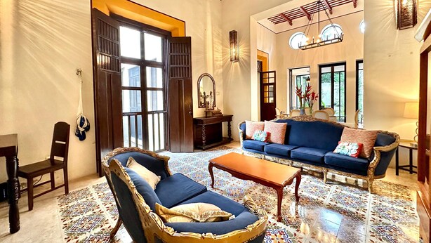 A spacious living room with a large blue sofa, a patterned rug, and a wooden coffee table. - Majestic Colonial Modern House@Santiago BELLE RIVE (Mérida)