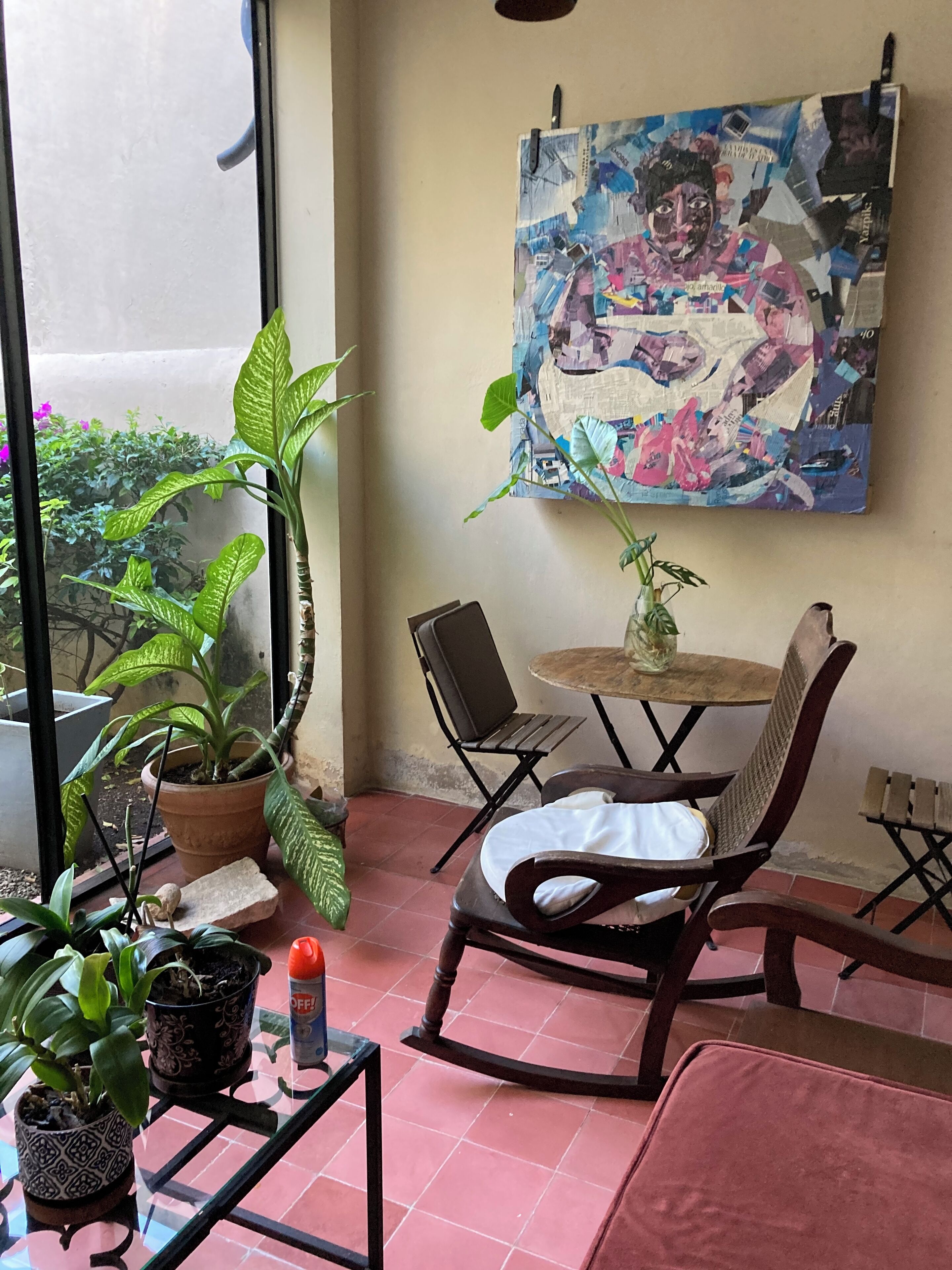 A cozy corner with a rocking chair, a small table, and various potted plants.