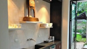 A modern kitchen with dark wood cabinets, a marble countertop, and a built-in oven. - Majestic Colonial Modern House@Santiago BELLE RIVE (Mérida)