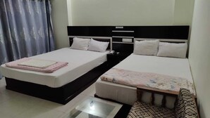 A hotel room with two single beds, a small table, and a chair. - Hotel Aman International (Kalapara)