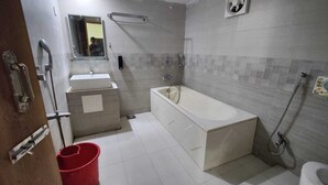 A bathroom with a bathtub, a sink, and a toilet. - Hotel Aman International (Kalapara)