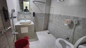 A small bathroom with a sink, toilet, and shower. - Hotel Aman International (Kalapara)