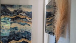 Une table en bois avec un vase bleu et une tasse, un tableau accroché au mur et une porte à l’arrière-plan.