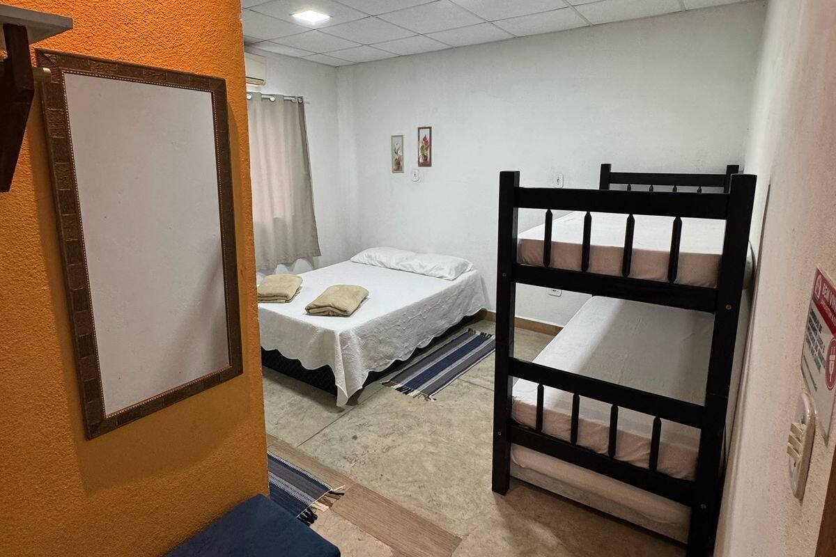 Ein Zimmer mit Etagenbett, einem Einzelbett, einem kleinen Tisch und einem an der Wand befestigten Fernseher.