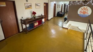 A hotel corridor with a wooden bench, artwork on the walls, and a sign indicating the hotel name. - Viva sol hospedagem  (Cabo Frio)