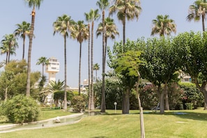 Stroll through the serene park, surrounded by lush greenery and a tranquil pond with a statue.