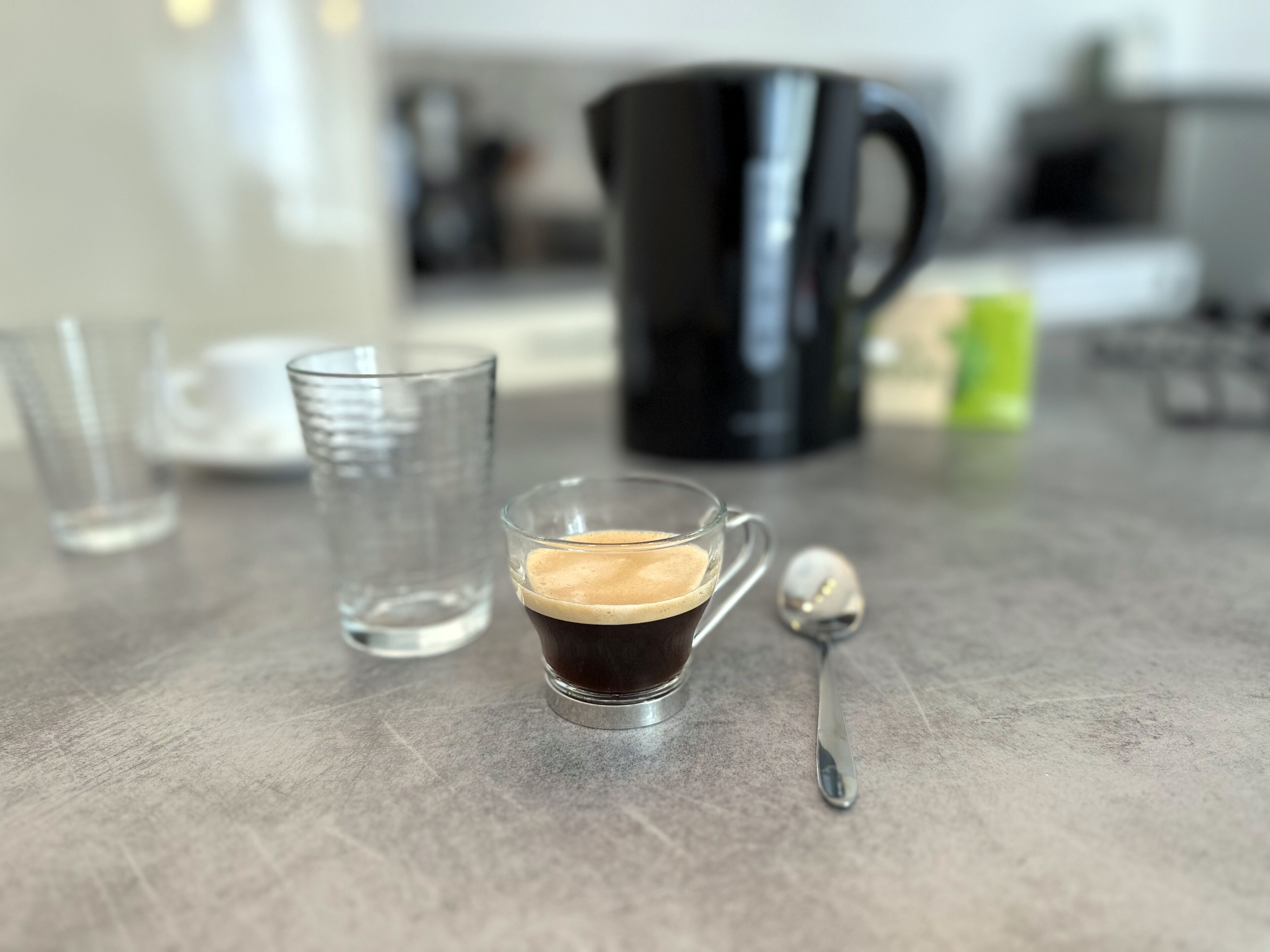 Una taza pequeña de café con una cuchara sobre una mesa.