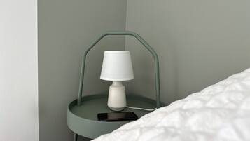A bedside table with a lamp and a smartphone on it.