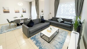 Un salon moderne avec un canapé gris, une table basse et un coin repas comprenant une table et des chaises.