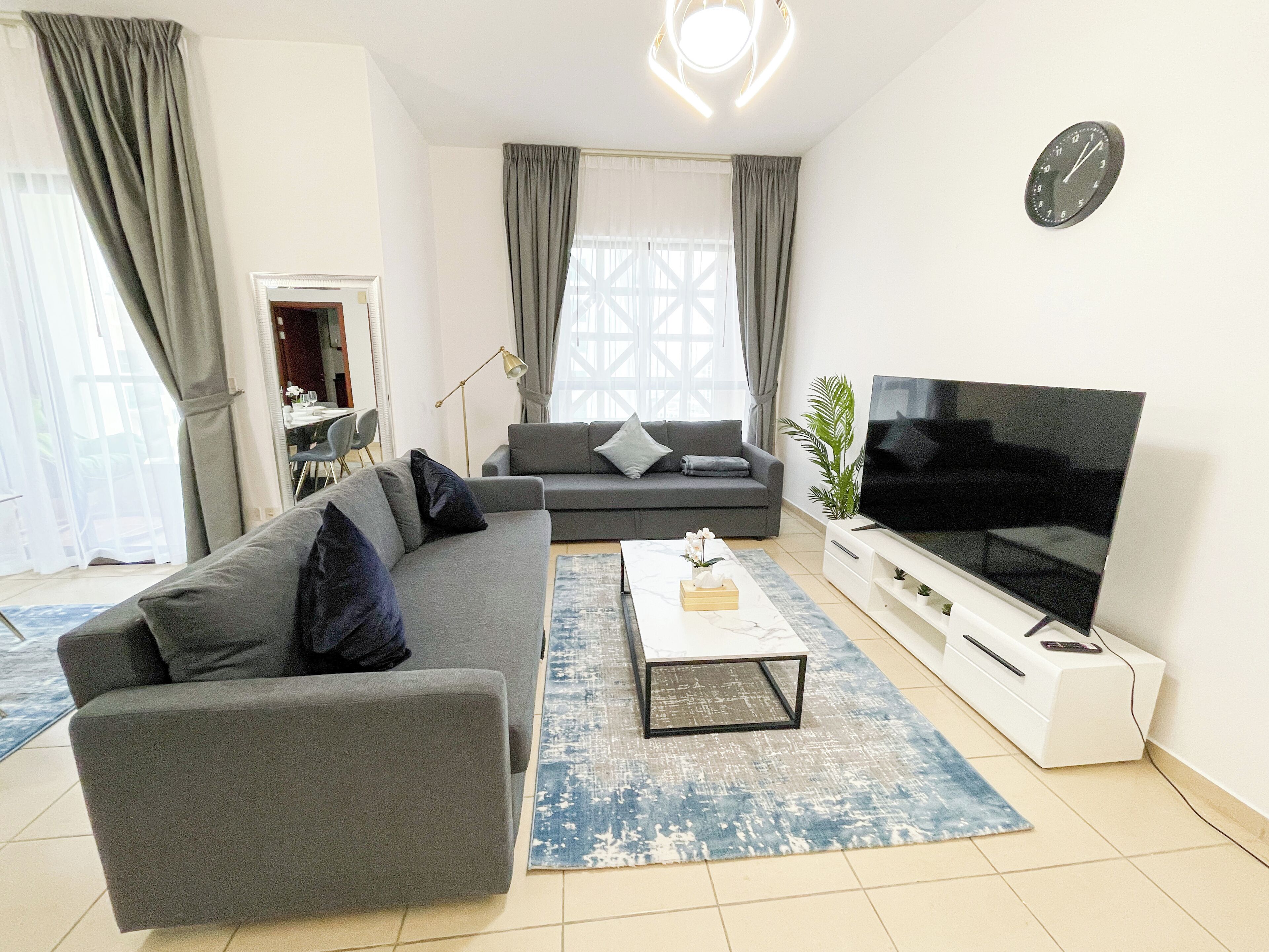 A modern living room with a grey sofa, a coffee table, and a flat-screen TV.