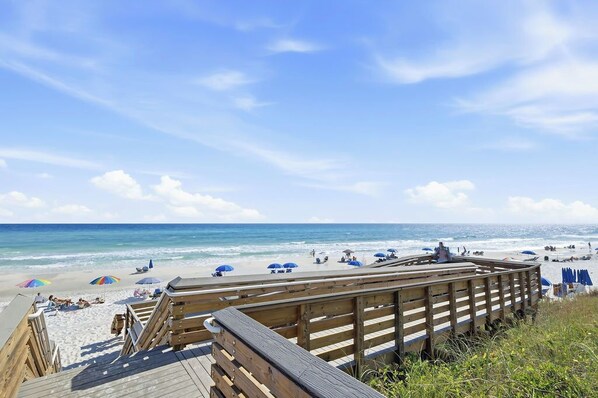 A wooden boardwalk leading to a beach with umbrellas and people. - 30A | Pool | Sunnyside Up | Walk to Beach| Golf Cart | Seagrove (Santa Rosa Beach)