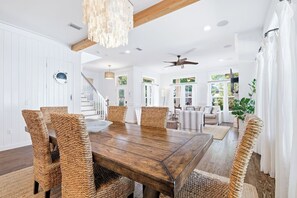 A dining area with a wooden table and wicker chairs, a ceiling fan, and a staircase leading to another room. - 30A | Pool | Sunnyside Up | Walk to Beach| Golf Cart | Seagrove (Santa Rosa Beach)