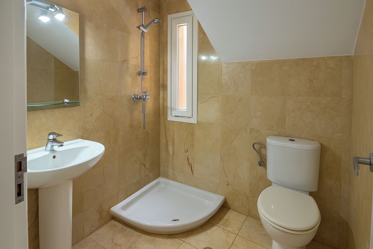 Un baño con ducha, lavamanos, inodoro y espejo.