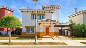 A two-story house with a white facade and yellow trim, a front porch, and a small tree in the yard. - Baron Villa With Private Heated Pool on Mar Menor (Torre-Pacheco)