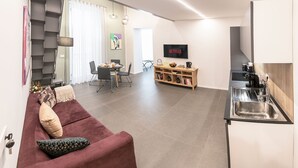 A modern living space with a sofa, dining table, and a kitchen area with a sink and coffee machine. - Three houses Toledo (Naples)