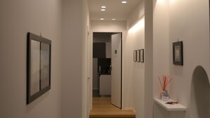 A narrow hallway with white walls, recessed lighting, and a wooden floor. - Three houses Toledo (Naples)