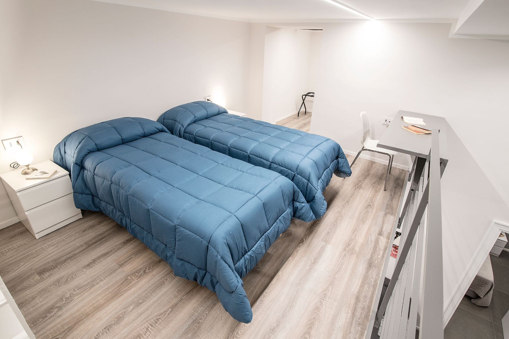 Un dormitorio con dos camas, un escritorio y una silla.