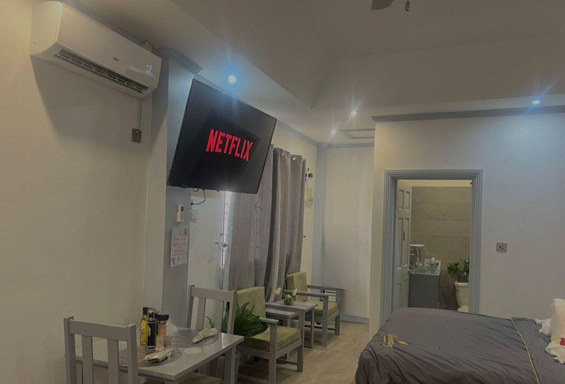 Camera d'albergo con un letto, una scrivania, una sedia, una TV a parete e un box doccia.
