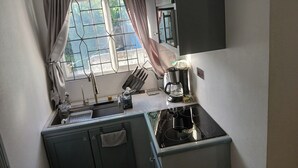 Una cocina compacta con ventana, un lavamanos, una cafetera y un juego de cuchillos.