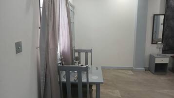 Een kamer met een grijze stoel, een klein tafeltje, een spiegel en een kast.