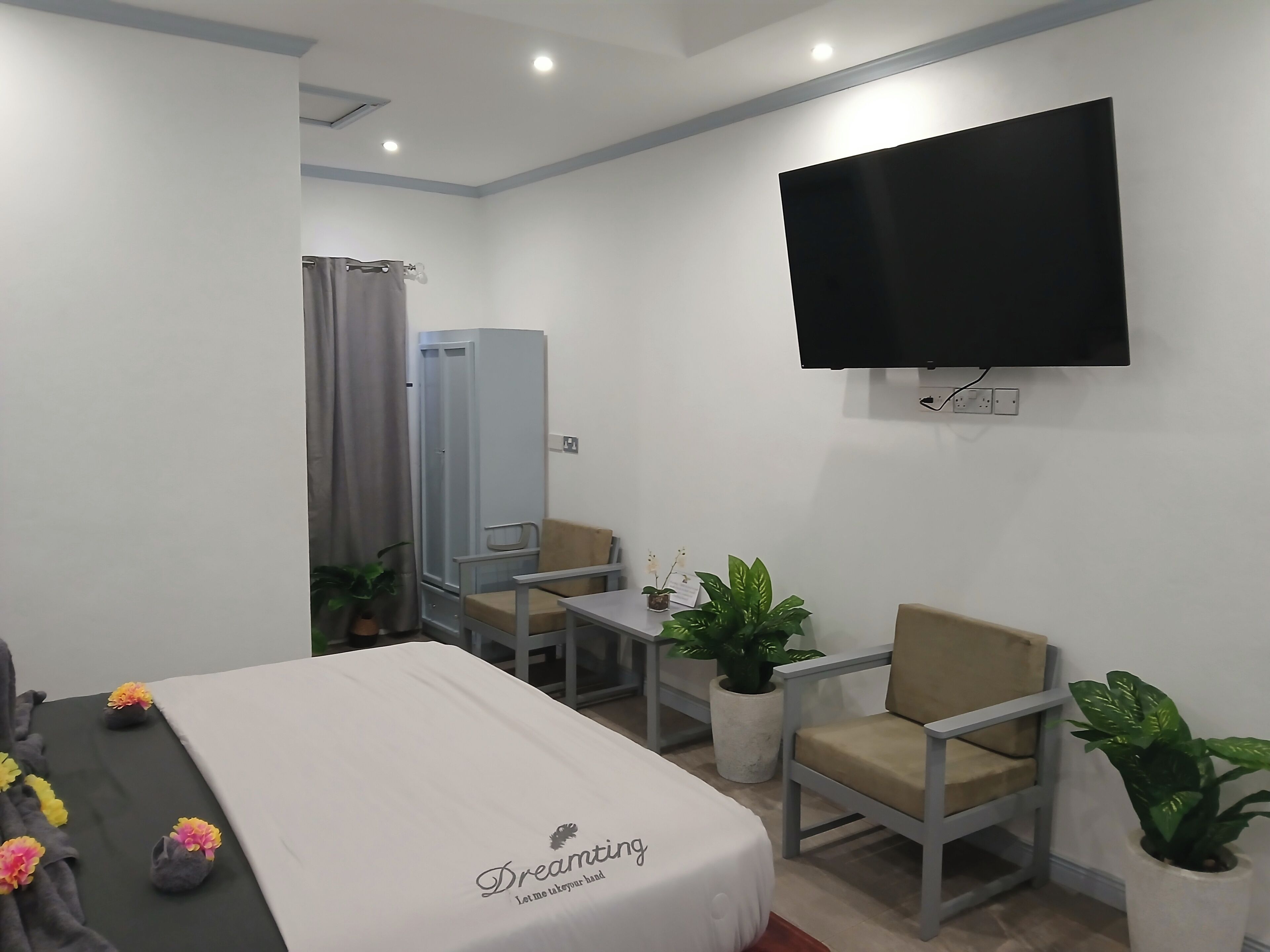Habitación de hotel con cama, escritorio, dos sillas, televisor y zona de ducha.