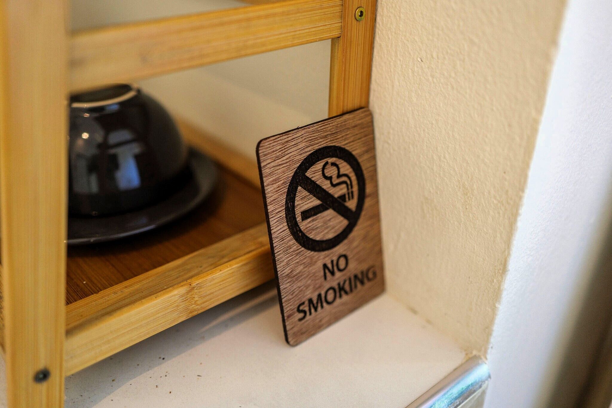 A wooden sign with a no-smoking symbol and text.