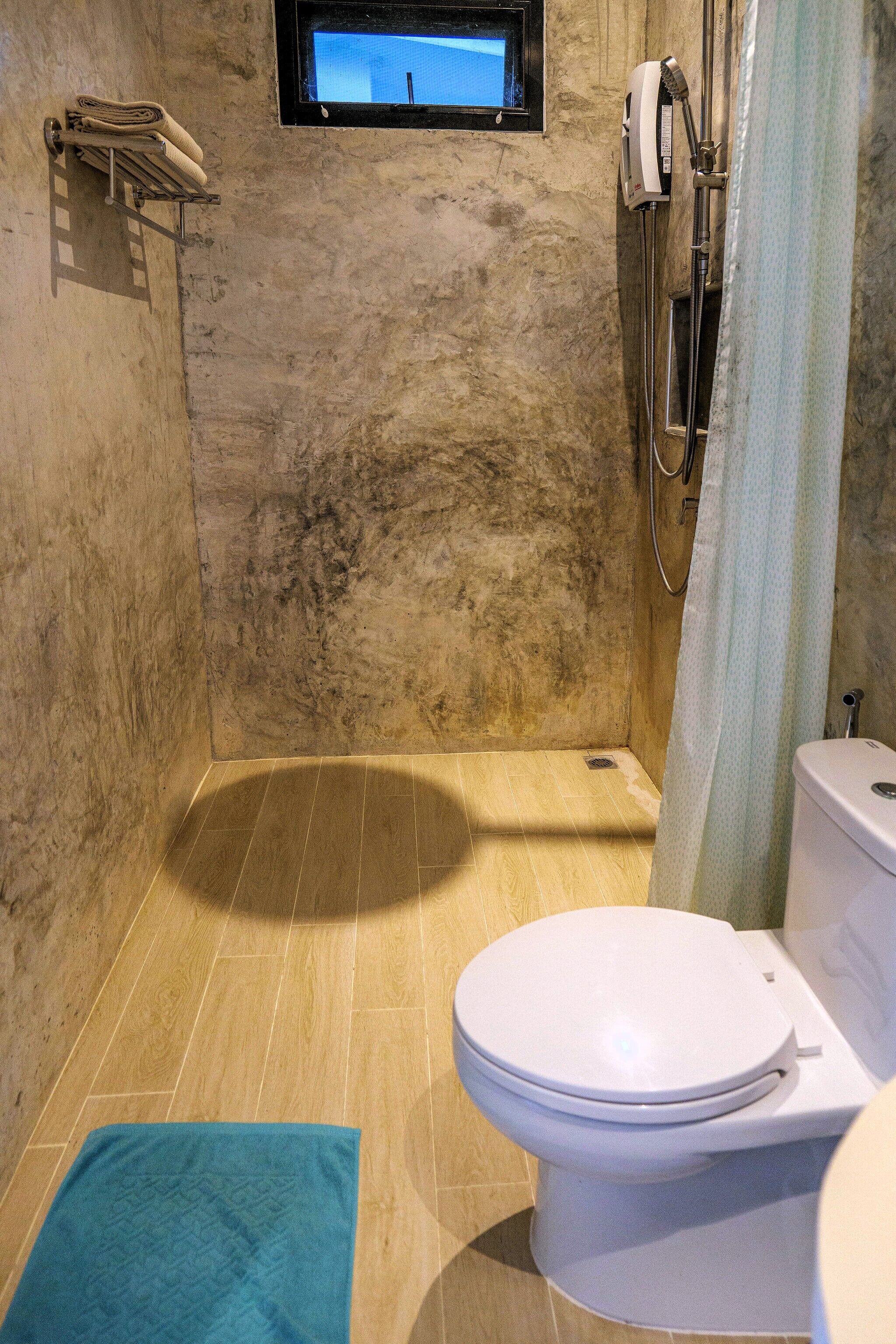 A bathroom with a shower, toilet, and a window above the sink.