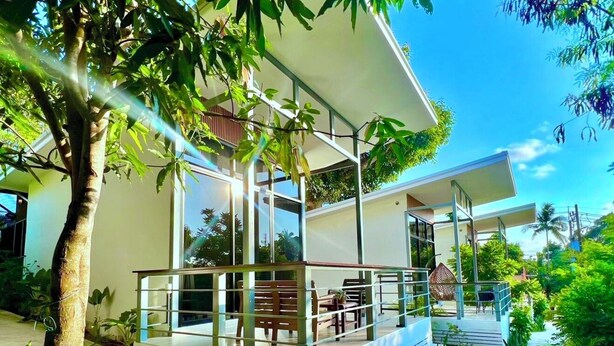 A modern house with a covered patio, a dining area, and a staircase leading to an upper level. - Modern Bungalows (Ko Chang)