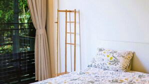 A bedroom with a bed, a window with curtains, and a view of greenery outside. - Modern Bungalows (Ko Chang)