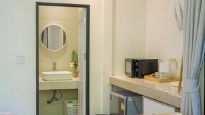 A compact bathroom with a sink, mirror, and a small refrigerator. - Modern Bungalows (Ko Chang)