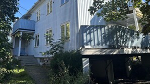 Een gebouw met twee verdiepingen, een overdekte veranda en een kleine voortuin.