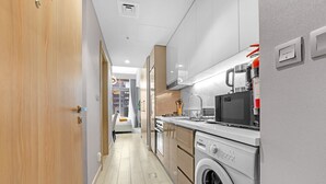 A modern kitchen with a washing machine, a microwave, and a gas switch on the wall. - Elegant Studio with Pool Access  Private Terrace (Dubai)