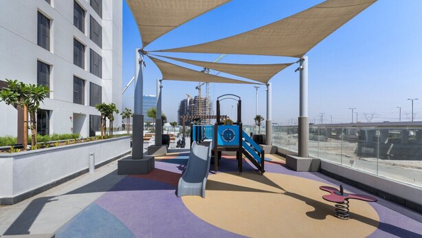 A rooftop playground with slides and climbing structures, surrounded by a white building and a clear sky. - Elegant Studio with Pool Access  Private Terrace (Dubai)