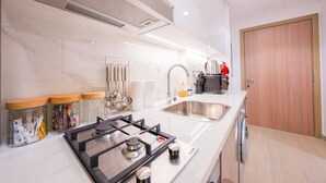 Ett modernt kök med en gasspis, två diskhoar och en diskmaskin. På bänkskivan står burkar med köksredskap.