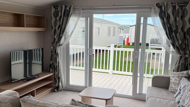 A modern living room with a sofa, a small table, and a TV stand. - Tranquil Seaside Caravan Retreat in Eyemouth (Eyemouth)