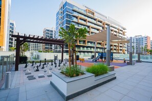 A modern outdoor area with a chessboard, seating, and a playground.