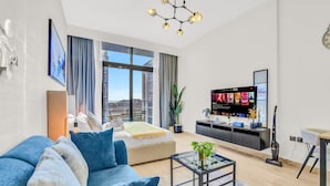 A modern living room with a sofa, a coffee table, a TV, and a large window. - Sleek Studio in Dubai (Dubai)