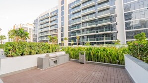 A modern residential building with multiple balconies, lush greenery, and a wooden deck area. - Chic Studio Oasis in Dubai (Dubai)
