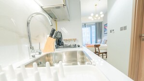 A modern kitchen with a stainless steel sink, a range, and a dining area with a table and chairs. - Chic Studio Oasis in Dubai (Dubai)