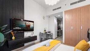 Una habitación de hotel moderna con cama, televisor, escritorio y armario.