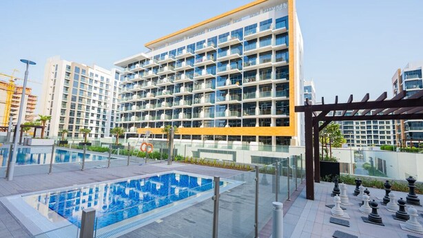Un hotel moderno con un amplio espacio de piscina, varios balcones y una vista despejada de los edificios circundantes.