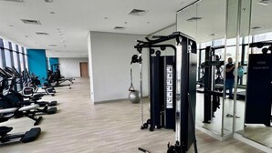 Een moderne sportschool met cardioapparatuur, losse gewichten en een spiegelwand.