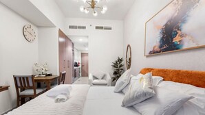Een hotelkamer met een groot bed, een bureau met stoel, een klok en een modern abstract schilderij.