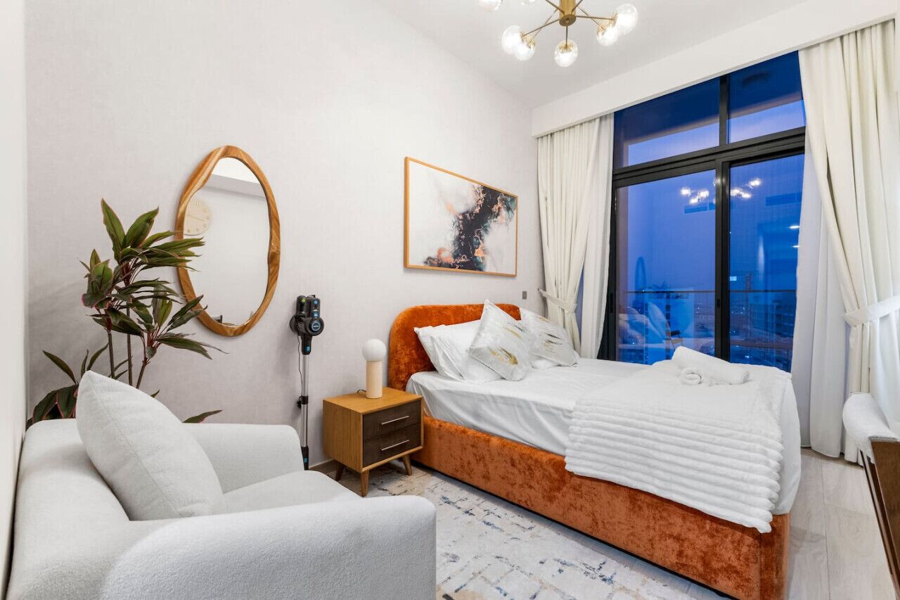 Una camera da letto moderna con un letto grande, un comodino, una sedia, uno specchio e una finestra con tende.